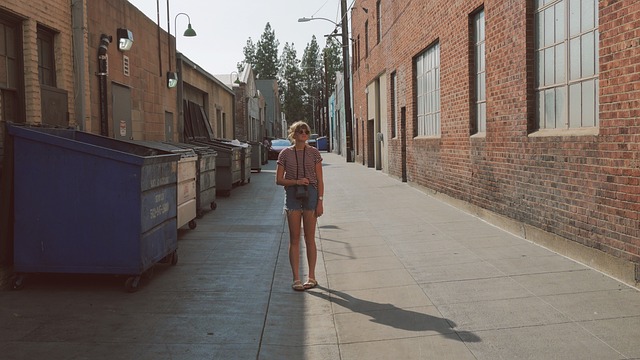 young female walking by an isle of dumpsters