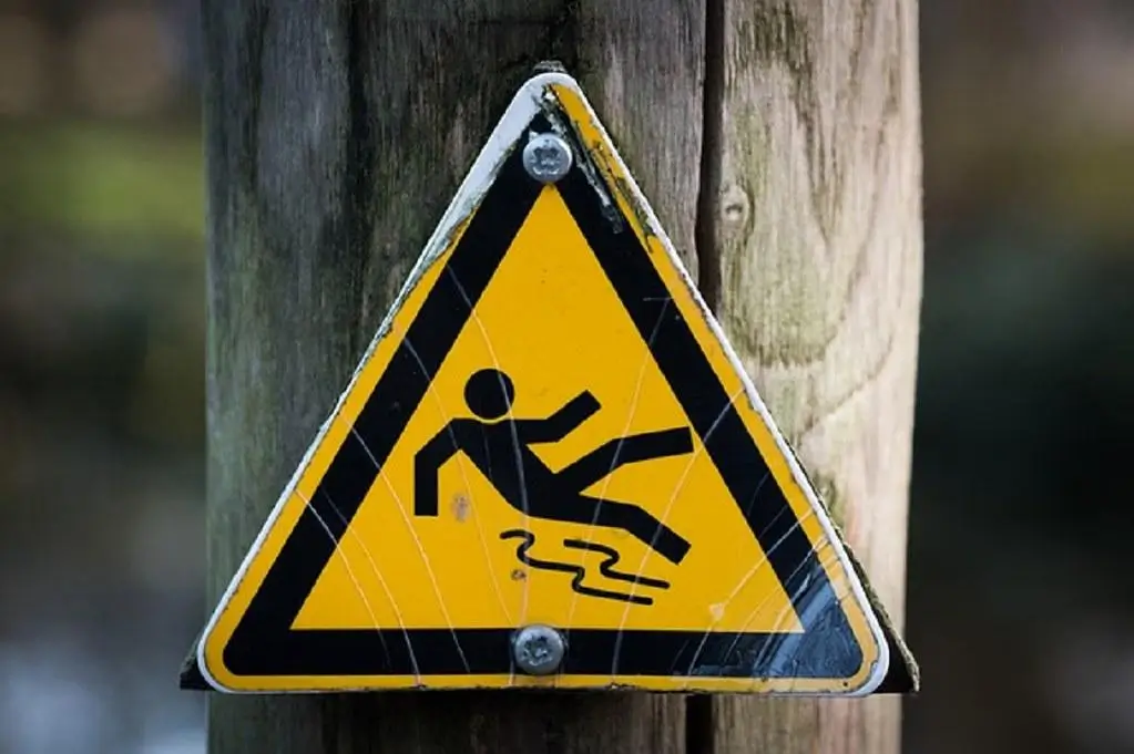 A photo of a slip hazard warning sign. Slip-and-fall hazard risks can be minimized with regular dumpster pad cleaning